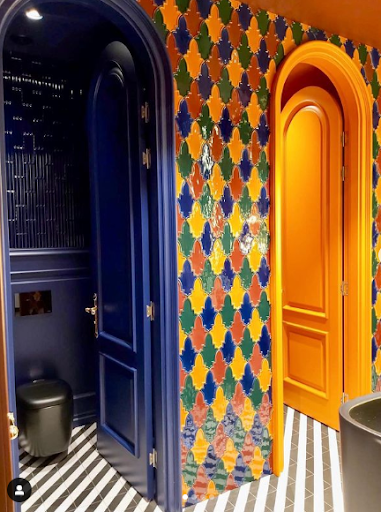 A colorful tiled bathroom with a black trash can Description automatically generated