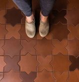 A person's feet standing on a tile floor Description automatically generated