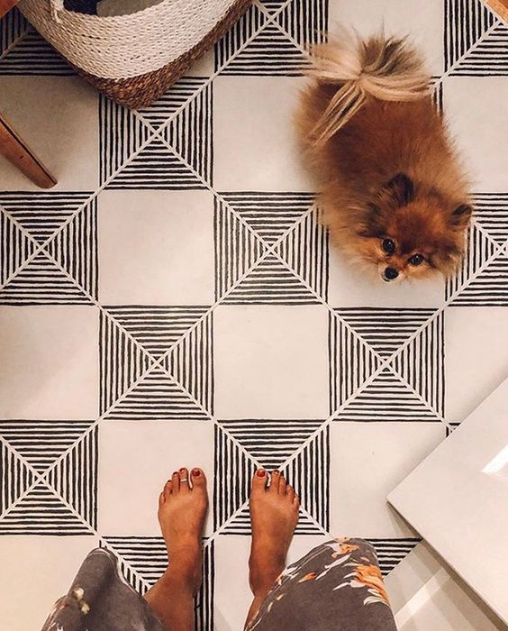 A dog and person's feet on a tile floor Description automatically generated